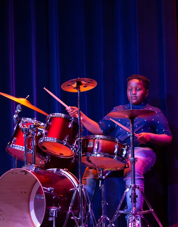 Young performer playing drums during the Male Talent Showcase